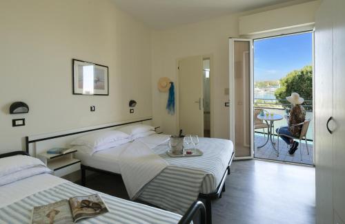 a hotel room with two beds and a balcony at Hotel Baltic in Cesenatico