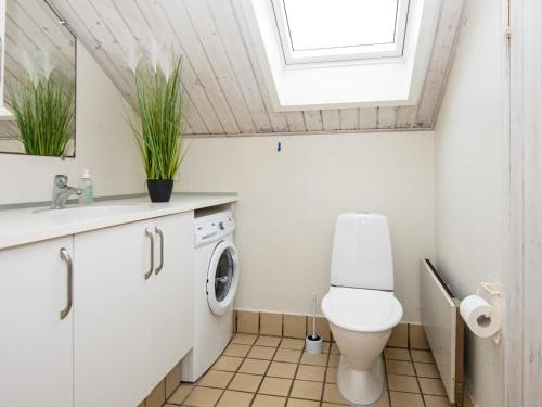 a bathroom with a toilet and a sink and a window at Four-Bedroom Holiday home in Hemmet 14 in Falen