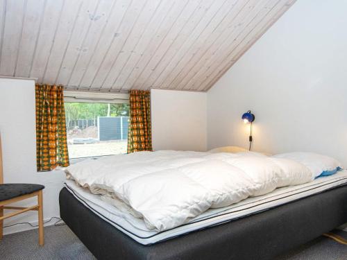 a bedroom with a large white bed with a window at Four-Bedroom Holiday home in Hemmet 14 in Falen