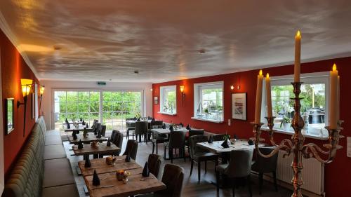 a restaurant with tables and chairs and red walls at Hotel Schleimünde in Kappeln