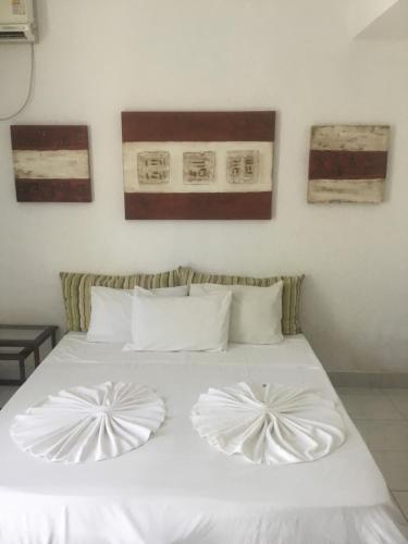 a white bed with two white pillows on it at Beverly Hills Flat in Porto Seguro