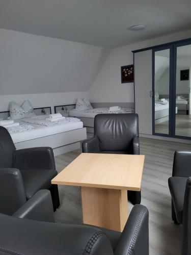 a room with a table and chairs and beds at Hotel Am Deich in Norddeich