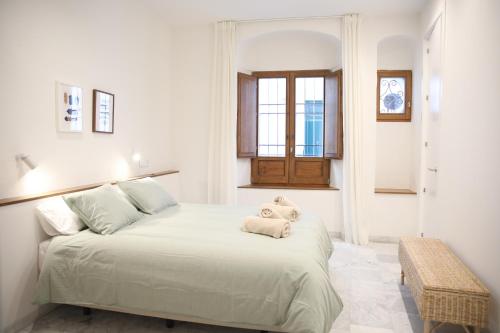 a white bedroom with a large bed with a window at Casa Arcadia in Córdoba