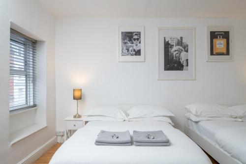 a white bedroom with two beds and a window at Soho & Covent Garden Apartment, Sleeps 3 in London
