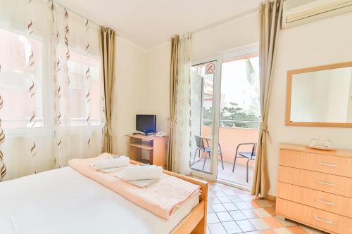 um quarto com uma cama branca e uma varanda em Garni Hotel Koral em Budva