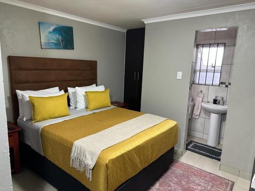 a bedroom with a bed with yellow pillows and a sink at The Hide in Roodepoort in Roodepoort