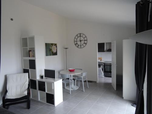- un salon avec une table et une horloge murale dans l'établissement Maison calme très belle vue Lavandou, au Lavandou