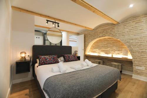 a bedroom with a large bed with a brick wall at RentalSevilla Magia en San Esteban in Seville