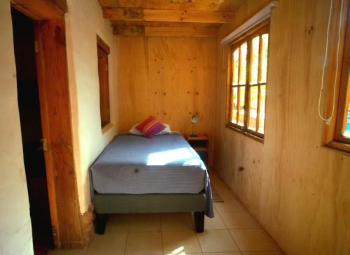 a small bedroom with a bed in a wooden room at Hotel-Camping Takha Takha in San Pedro de Atacama