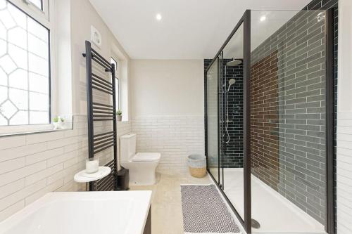 a bathroom with a shower and a toilet and a tub at Beautiful Beach Side 4 Bed House in Kent