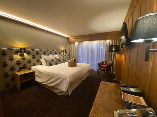 a hotel room with a bed and a table at Hôtel Macchi Restaurant & Spa in Châtel