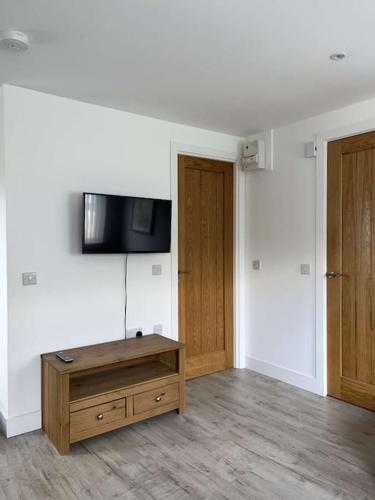 a living room with a tv on a wall at Lovely one bed, open plan studio apartment. in Culloden