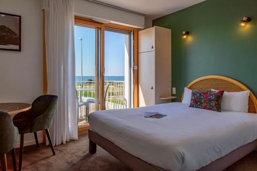 a bedroom with a bed and a balcony with the ocean at Hôtel l'Albatros in Damgan