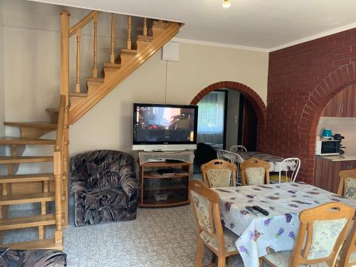 a living room with a dining room table and a television at Attila Vendégház in Kiskunmajsa