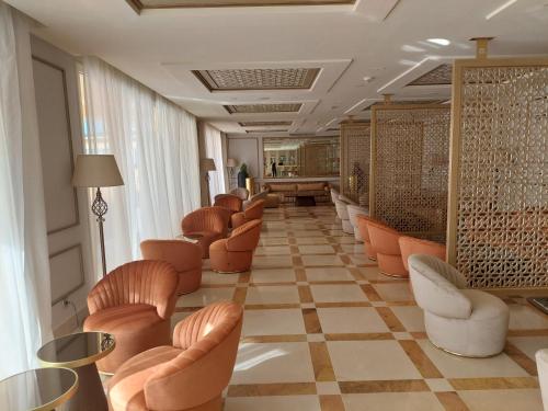 a waiting room with orange chairs and a checkerboard floor at Royal Tulip Korbous Bay Thalasso & Springs in Qurbuş