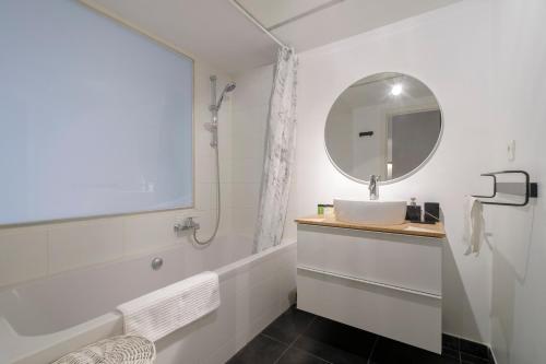 ein weißes Badezimmer mit einem Waschbecken und einem Spiegel in der Unterkunft Charmant Studio proche de la Toison d'Or in Brüssel