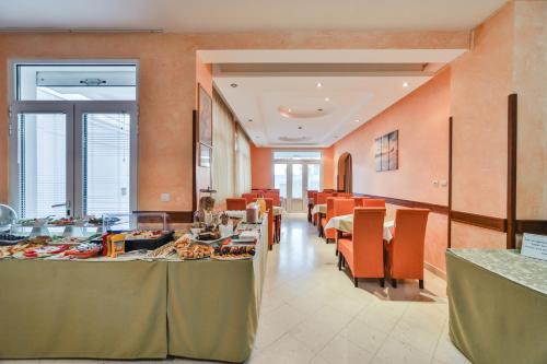 uma sala de jantar com mesas e paredes cor de laranja em Garni Hotel Koral em Budva