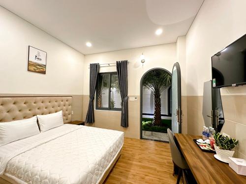 1 dormitorio con cama, escritorio y ventana en VÂN TRANG GARDEN HOTEL 2, en Vĩnh Long