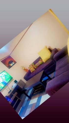 een woonkamer met een paarse bank en een tafel bij Sassy's Hub in Kakamega