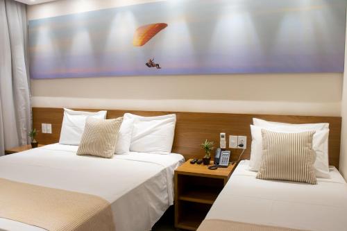 2 camas en una habitación de hotel con una foto en la pared en Porto das Asas Park Hotel, en Andradas