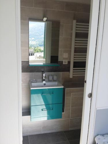 ein Badezimmer mit einem blauen Waschbecken und einem Fenster in der Unterkunft Appartement avec vue imprenable sur la montagne in Argelès-Gazost