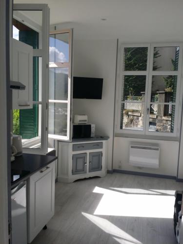 - une cuisine avec des placards blancs et 2 grandes fenêtres dans l'établissement Appartement avec vue imprenable sur la montagne, à Argelès-Gazost