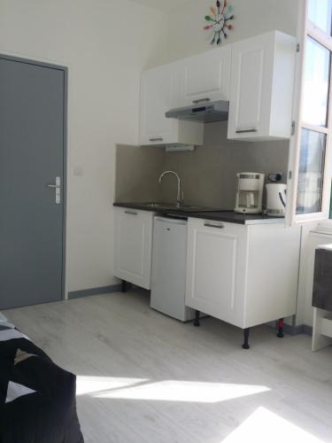eine Küche mit weißen Schränken und einem Waschbecken in der Unterkunft Appartement avec vue imprenable sur la montagne in Argelès-Gazost