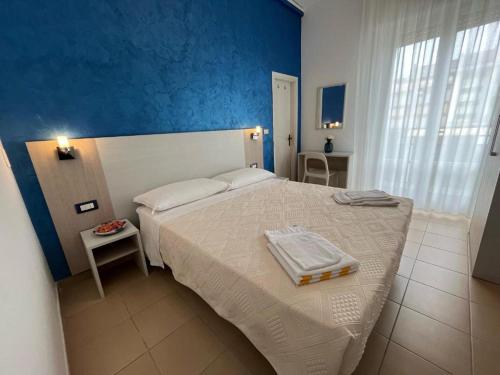 een slaapkamer met een wit bed en een blauwe muur bij Hotel Le Ali in Rimini