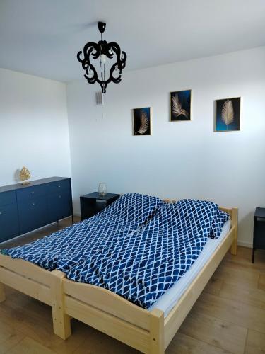a bedroom with a bed with a blue comforter at Apartament Oliwia in Grywałd