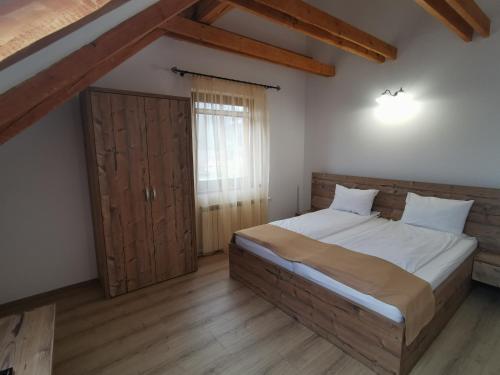 ein Schlafzimmer mit einem großen Bett und einer Holztür in der Unterkunft Hanul Greweln in Mediaş