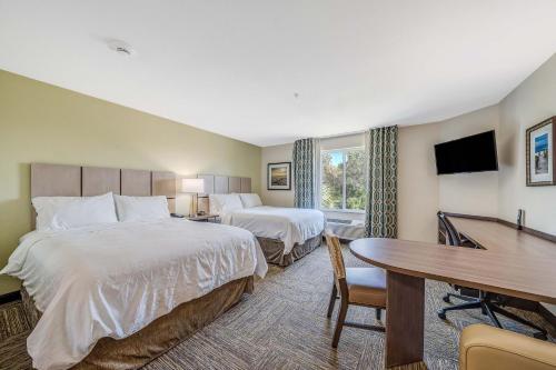 a hotel room with two beds and a desk at Candlewood Suites - Panama City Beach Pier Park, an IHG Hotel in Panama City Beach