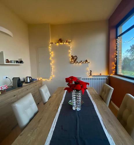 a table with a vase with red flowers on it at Villetta verde Smeraldo in Vignale Monferrato
