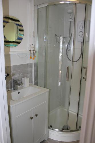 a white bathroom with a shower and a sink at Lil' Nauti in Pentewan