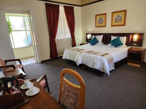 pokój hotelowy z łóżkiem i stołem w obiekcie Royal Hotel Ladysmith w mieście Ladysmith