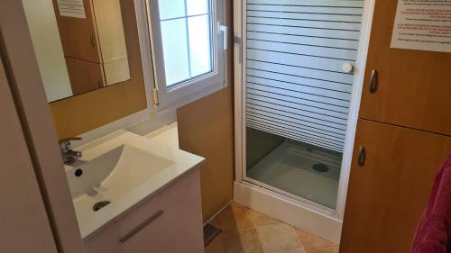 een badkamer met een wastafel, een spiegel en een raam bij Camping Le Saint Clair in Moustiers-Sainte-Marie