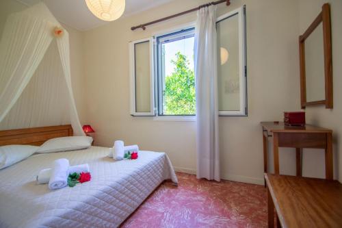 Doras Beach Bungalow B في بلانوس: غرفة نوم بسرير وملاءات بيضاء ونافذة