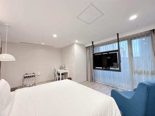 a bedroom with a large white bed and a tv at 台南星鑽國際商旅 Hua Hotel in Tainan
