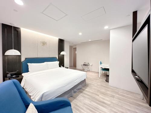 a bedroom with a large bed and a blue chair at 台南星鑽國際商旅 Hua Hotel in Tainan