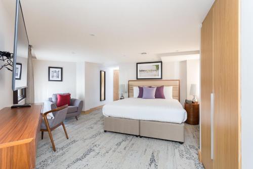 a hotel room with a bed and a desk and a room at Sanctum Belsize Road in London