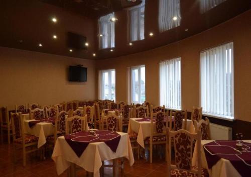ein Zimmer mit Tischen und Stühlen sowie weißen Tischdecken in der Unterkunft Мотель ОК in Shepetivka