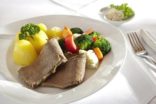 a plate of food with meat and vegetables on a table at Gasthof Lerner in Freising