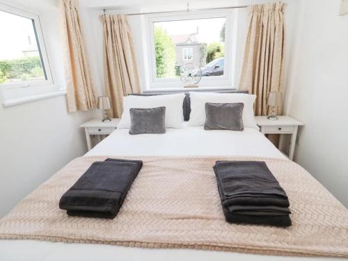 a bedroom with a white bed with two pillows on it at North View Cottage next to Hadrian's Wall in Gilsland