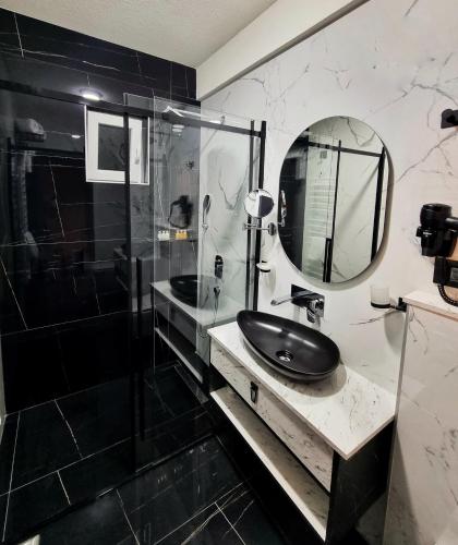 a black and white bathroom with a sink and a mirror at Dream House Hotel & Spa in Kolašin
