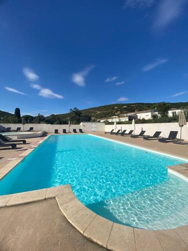 a swimming pool with blue water and lounge chairs at Résidence Les Pavillons du Golfe in Favone