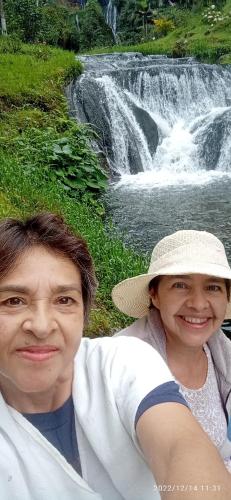 a man and a woman sitting in front of a waterfall at HOSTAL CASA VICTORIA PIJAO in Pijao