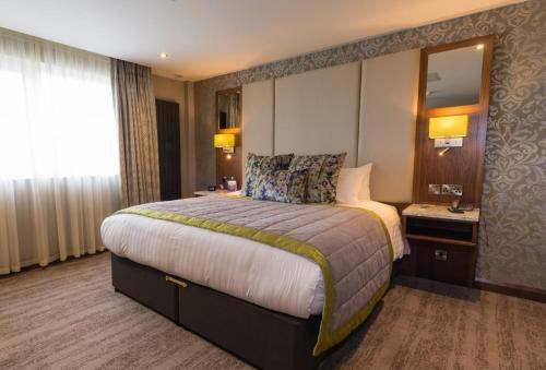 a hotel room with a large bed and a mirror at The Valley Hotel & Carriage Gardens in Fivemiletown