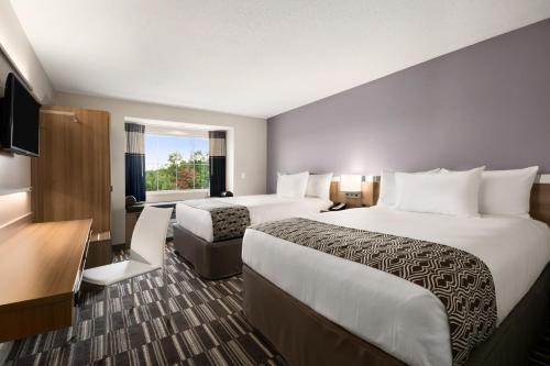 a hotel room with two beds and a desk at Microtel Inn & Suites by Wyndham in Lynchburg