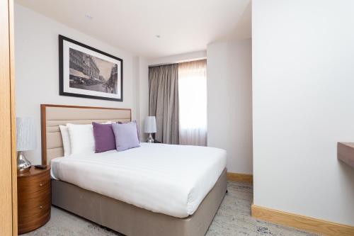 a bedroom with a large white bed with purple pillows at Sanctum Belsize Road in London