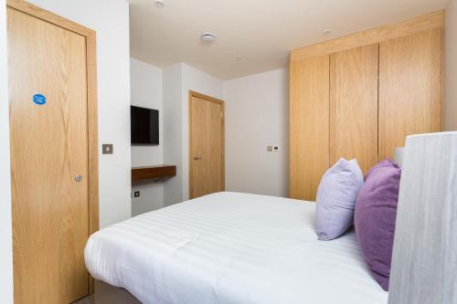 a bedroom with a large white bed with purple pillows at Sanctum Belsize Road in London