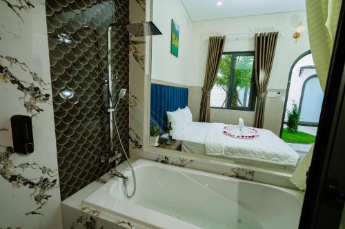 a bathroom with a tub and a bed in a mirror at VÂN TRANG GARDEN HOTEL 2 in Vĩnh Long